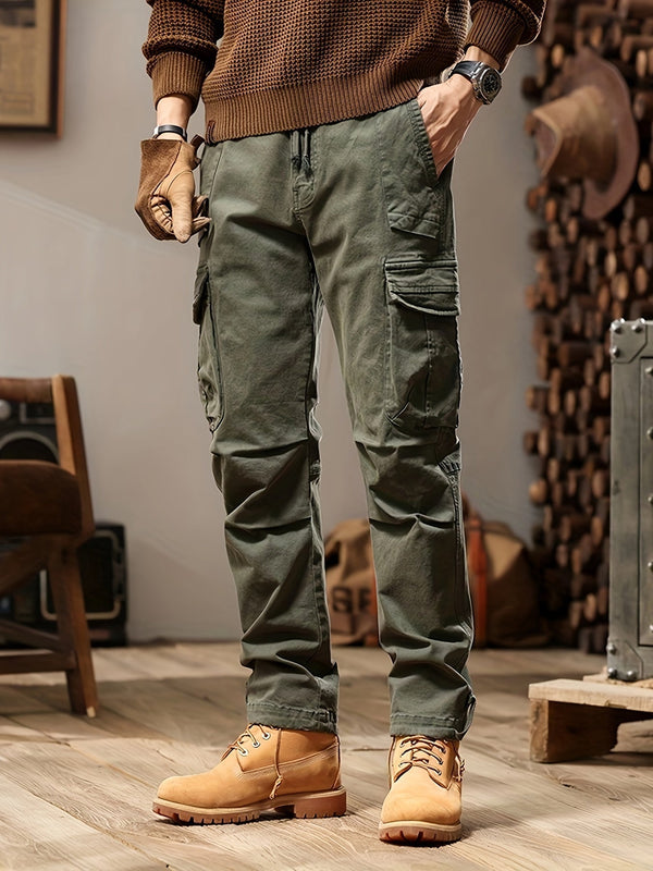 Man in groene cargobroek en bruine trui, draagt bruine laarzen en handschoenen, casual herenkleding, modetrends, comfortabele outdoorstijl.