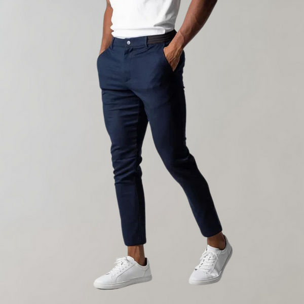 Donkerblauwe herenbroek, slim fit, gedragen met witte sneakers en een wit T-shirt. Stijlvolle casual outfit voor mannen.