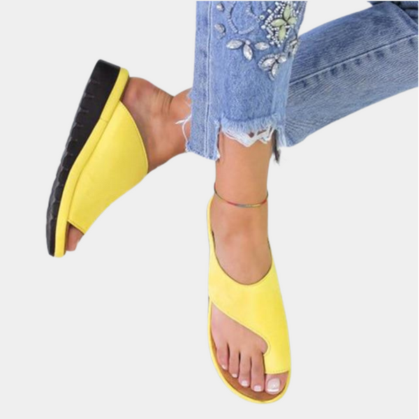 Gele dames sandalen met open teen en zwarte zool, gedragen met geborduurde jeans. Comfortabele zomerschoenen, modieus en casual.