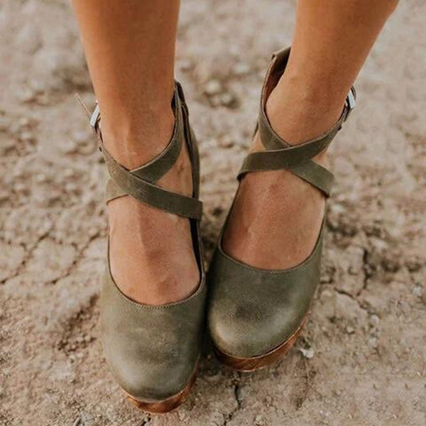 Groene leren damesschoenen met kruisbanden op een zanderige ondergrond. Comfortabele, stijlvolle schoenen voor dagelijks gebruik.