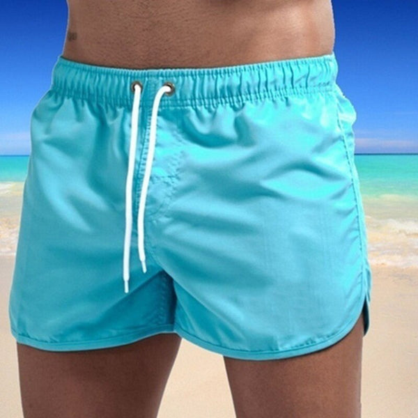Turquoise zwembroek voor heren op strand, elastische tailleband met witte trekkoorden, zomerse strandmode, comfortabele zwemkleding.