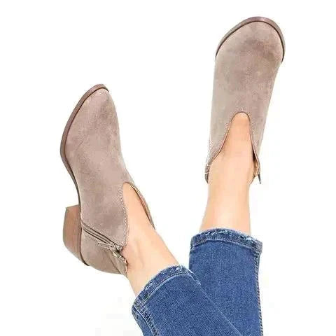 Beige suède V-cut enkellaarsjes met blokhak, gedragen met blauwe jeans. Stijlvolle dameslaarzen, perfect voor casual en trendy outfits.