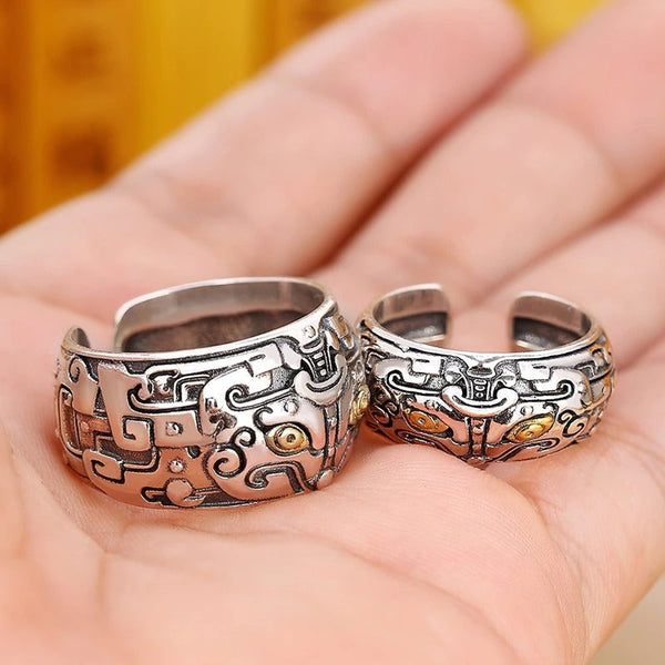 Twee zilveren tribale ringen met ingewikkeld patroon en gouden accenten, gepresenteerd op een hand. Perfect voor unieke sieradenliefhebbers.