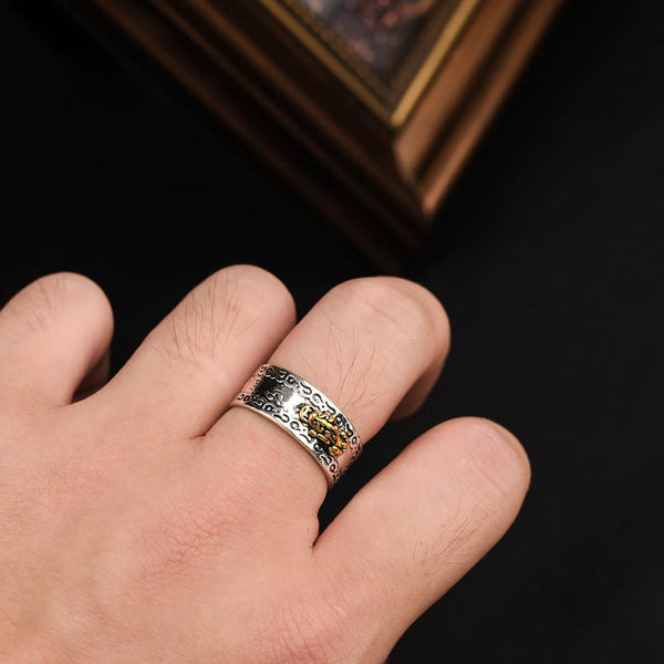 Zilveren herenring met gedetailleerd patroon en gouden accenten, gedragen op een hand. Stijlvolle sieraden voor mannen, elegant design.