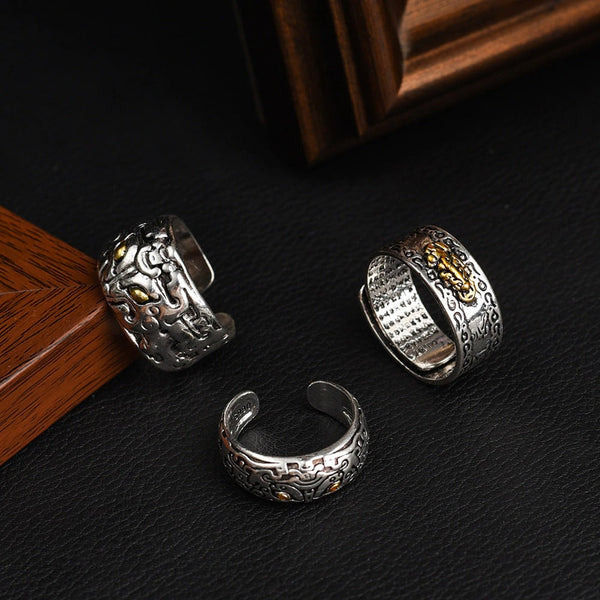 Drie zilveren vintage ringen met gegraveerde patronen en gouden accenten op een zwarte achtergrond, perfect voor stijlvolle sieradenliefhebbers.