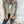 Vrouw in beige corduroy jack met capuchon, witte top en donkere jeans tegen verweerde muur. Modieuze herfstkleding, casual damesstijl.