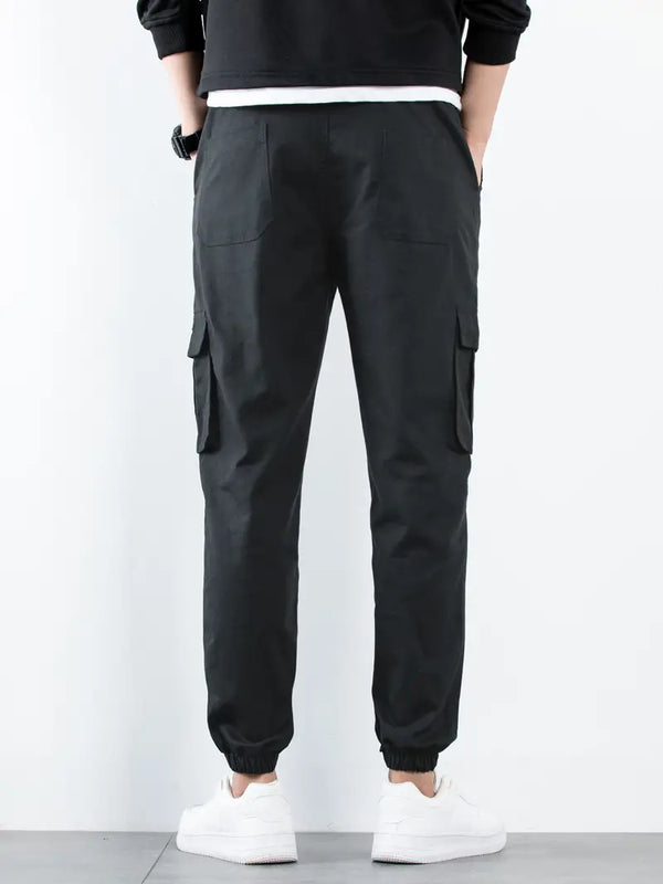 Zwarte cargobroek voor heren, achteraanzicht, met elastische enkels en zakken, gedragen met witte sneakers. Casual herenkleding.