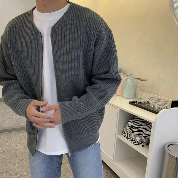 Man in grijze gebreide trui met witte T-shirt en blauwe jeans in moderne keuken. Casual herenkleding, stijlvolle outfit, comfortabele mode.