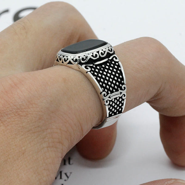 Zilveren herenring met zwart onyx, gedetailleerd filigraan ontwerp, gedragen aan een hand. Stijlvolle sieraden voor mannen, elegant en tijdloos.