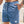 Man in blauwe corduroy korte broek met witte trekkoord, hand in zak. Zomermode, casual herenkleding, strandstijl.