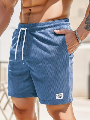 Man in blauwe corduroy korte broek met witte trekkoord, hand in zak. Zomermode, casual herenkleding, strandstijl.