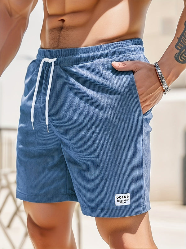 Man in blauwe corduroy korte broek met witte trekkoord, hand in zak. Zomermode, casual herenkleding, strandstijl.