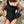 Zwarte asymmetrische badpak met rozen, vrouw poseert op rotsen, strandmode, elegante zwemkleding, zomerstijl, luxe badmode, strandvakantie.