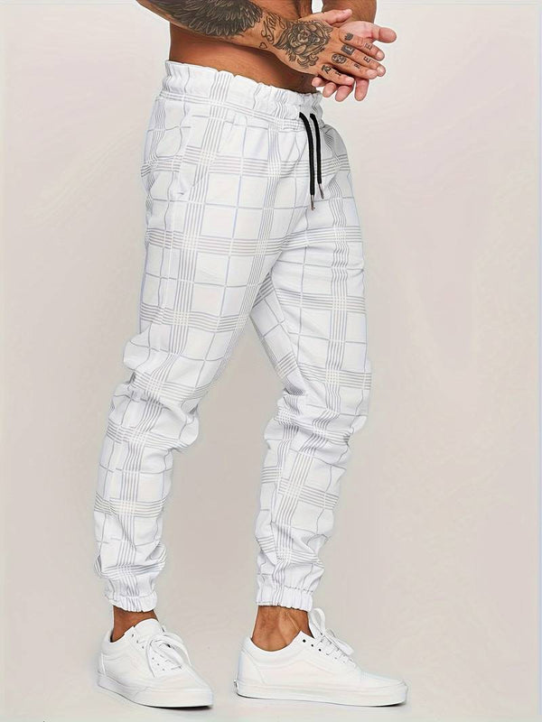 Witte geruite joggingbroek voor heren, met elastische tailleband en zwarte trekkoord, gecombineerd met witte sneakers. Comfortabele sportieve stijl.