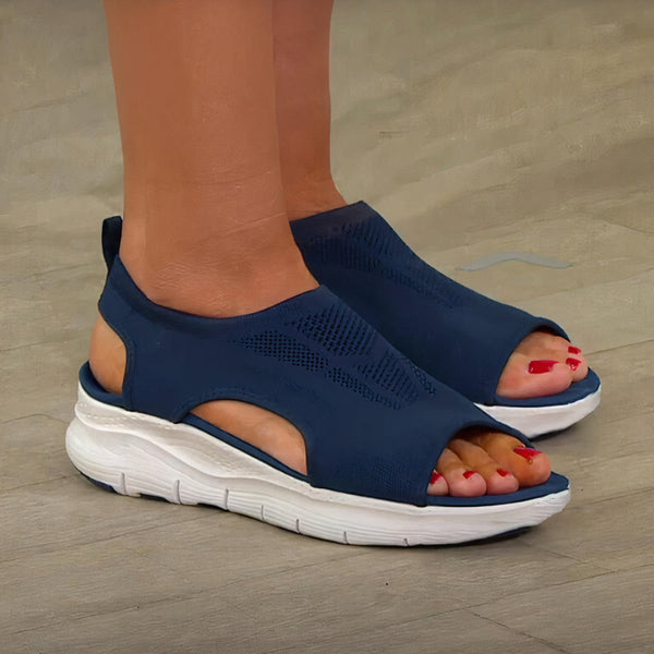 Donkerblauwe sandalen met open teen en dikke witte zool, gedragen op een houten vloer. Comfortabele zomerschoenen voor dames, ideaal voor dagelijks gebruik.