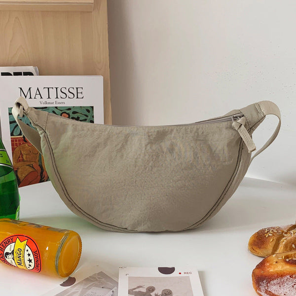 Beige crossbody tas op tafel met tijdschriften, frisdrank en broodjes. Stijlvolle schoudertas, ideaal voor dagelijks gebruik en modeaccessoires.