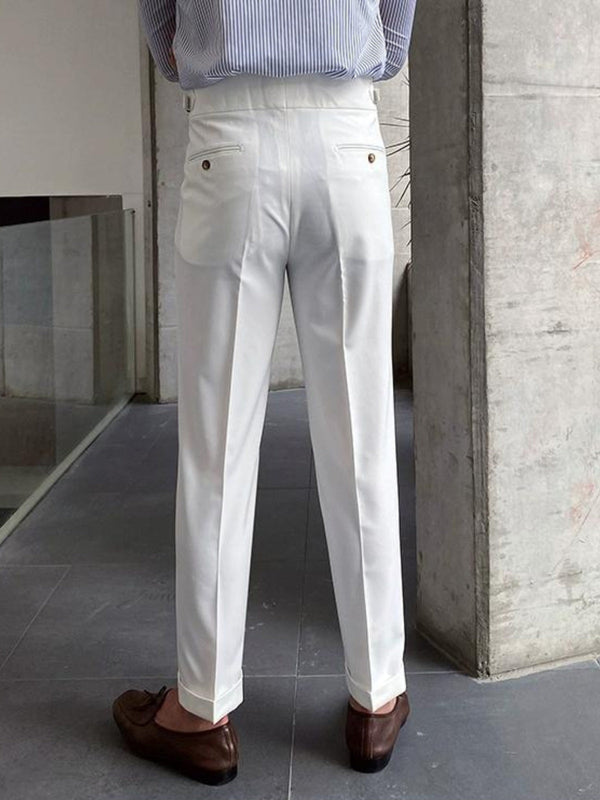 Man in witte broek en bruine loafers, staand in moderne ruimte. Stijlvolle herenmode, zakelijke kleding, minimalistisch design.