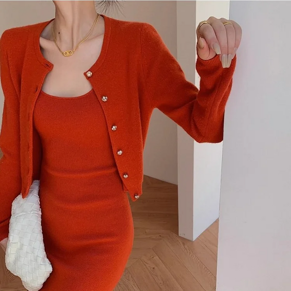 Oranje gebreide jurk en vest set, vrouw met witte gevlochten clutch, stijlvolle herfstmode, elegante dameskleding, trendy outfit.