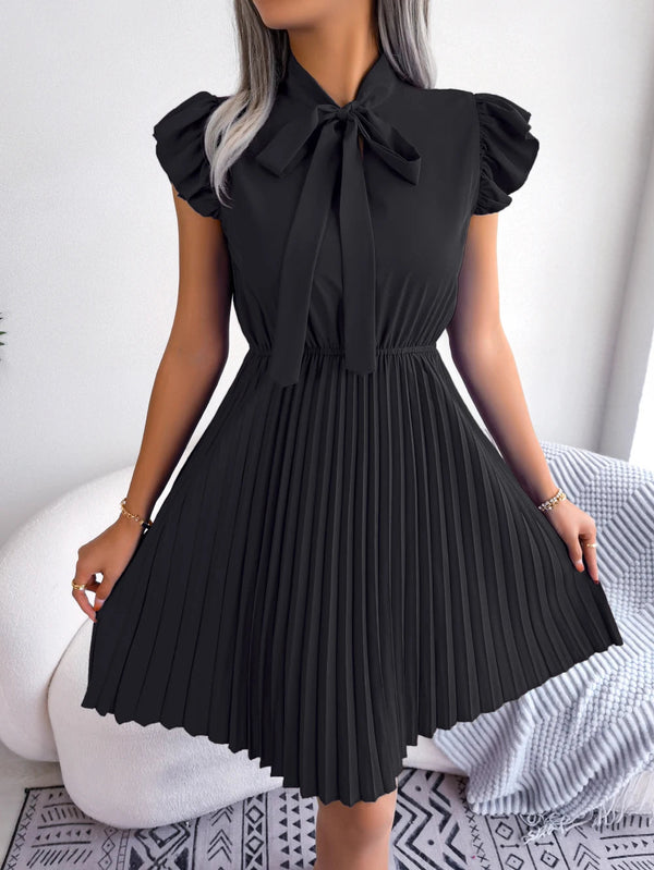 Zwarte geplooide jurk met strik, korte mouwen en elegante uitstraling. Perfect voor formele gelegenheden. Modieuze dameskleding, stijlvolle outfit.