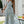 Vrouw in zomerse bloemenjurk met blauwe en witte print, lachend in tuin. Perfecte outfit voor zonnige dagen. Zomerjurk, casual mode, buitenkleding.