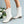 Witte dameslaarzen met blokhak, gemaakt van leer, naast witte bloemen op een lichtblauwe achtergrond. Trendy en stijlvolle schoenen voor dames.
