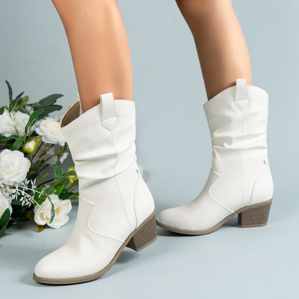 Witte dameslaarzen met blokhak, gemaakt van leer, naast witte bloemen op een lichtblauwe achtergrond. Trendy en stijlvolle schoenen voor dames.