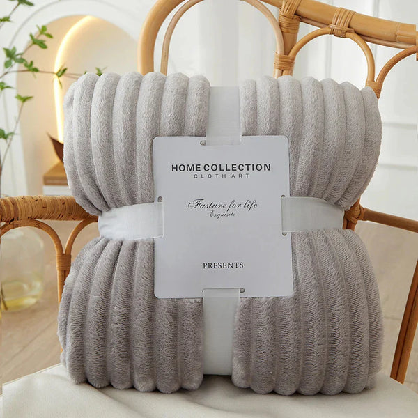 Grijze fleece deken van Home Collection, elegant verpakt op een houten stoel. Perfect voor woondecoratie en comfort. Ideaal voor cadeau-ideeën.