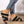 Zwarte gevlochten sandalen met sleehak, gedragen door een persoon in blauwe jeans met ritsdetail. Comfortabele zomerschoenen voor dames.