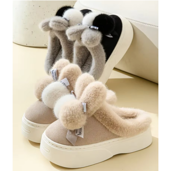 Pluche pantoffels met dikke zolen, beige en grijs, met decoratieve pompons. Comfortabele winterse huisschoenen voor dames. Trendy en warm.