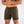 Mannelijke model draagt olijfgroene sportshorts met trekkoord en zakken, ideaal voor fitness en casual wear. Comfortabele en stijlvolle herenkleding.