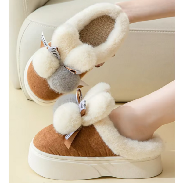 Bruine en witte pluche pantoffels met dikke zolen en decoratieve strik, ideaal voor wintercomfort en warme voeten. Perfecte huisschoenen voor dames.