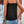 Vrouw in zwarte kanten top en denim shorts, zomerse outfit, casual mode, buiten bij houten deur en bloemen. Perfect voor warme dagen.