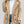 Vrouw draagt een trendy, beige teddyjas met dubbele knopen, gecombineerd met een witte trui en spijkerbroek. Perfect voor herfstmode en casual stijl.