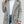 Grijze teddyjas voor dames, dubbelrij knopen, casual wintermode, gecombineerd met witte trui en spijkerbroek. Perfect voor koude dagen.