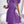 Vrouw in paarse geplooide jurk met strik, gouden kettingtas, moderne mode, elegante kleding, trendy outfit, stijlvolle dameskleding.