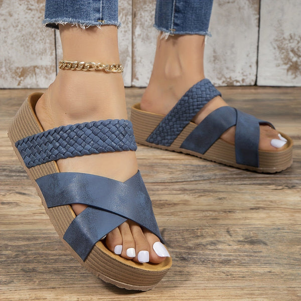 Blauwe dames sandalen met gevlochten band en sleehak, gedragen met enkelbandje. Comfortabele zomerschoenen op houten vloer.