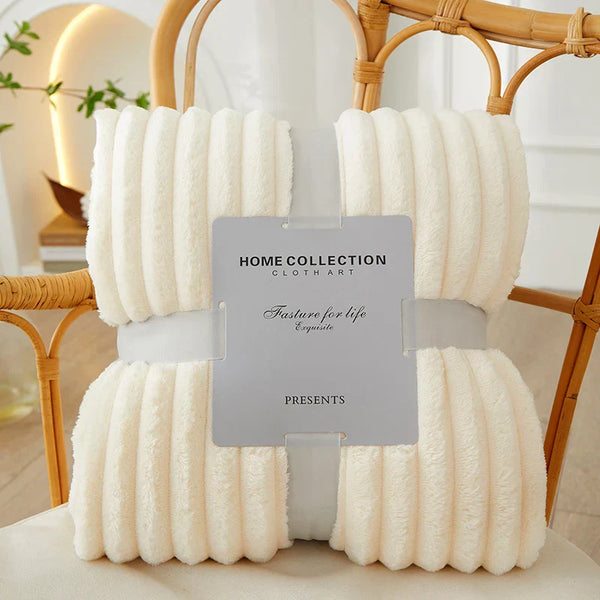 Witte fleece deken op rotan stoel, Home Collection label, zachte textuur, interieurdecoratie, comfortabele woonaccessoires, moderne stijl.