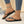 Zwarte teenslippers met vlinderdecoratie, gedragen door vrouw met witte nagellak en turquoise enkelbandje, naast een discobal op beige achtergrond.