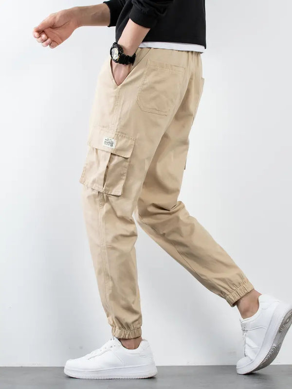 Beige cargobroek voor heren, zijaanzicht. Casual stijl, elastische enkels, meerdere zakken. Perfect voor dagelijks gebruik. Comfortabele pasvorm.