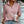 Vrouw in roze geribbelde trui met opstaande kraag, houdt een witte koffiebeker vast. Casual mode, herfstkleding, trendy damesoutfit.