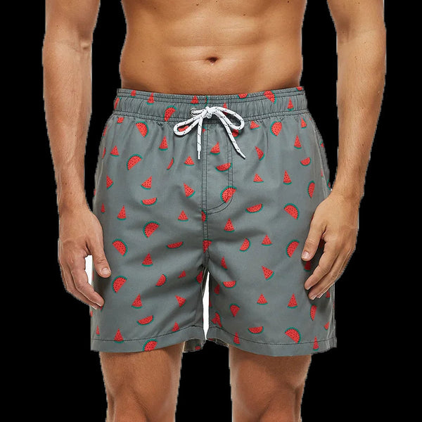Grijze zwembroek met rode watermeloenprint, gedragen door een man. Trendy zwemkleding voor heren, ideaal voor strand en zwembad.