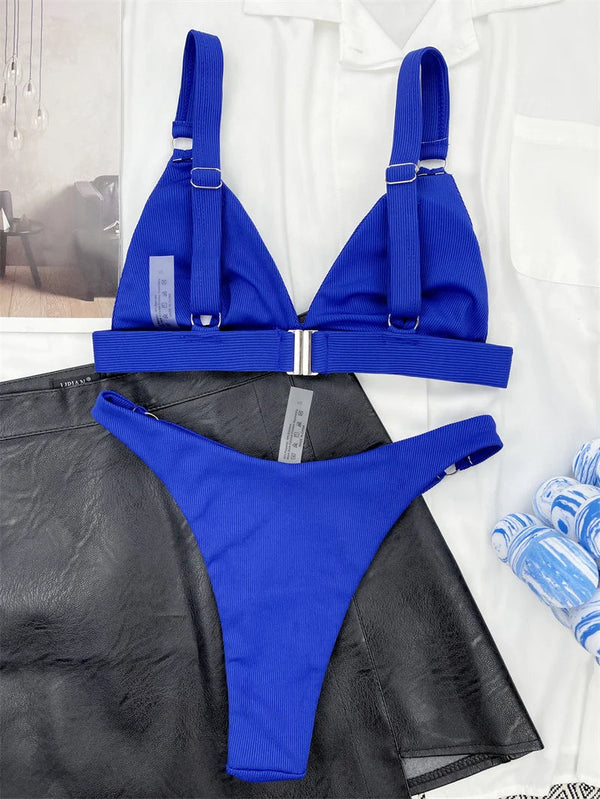 Blauwe bikini set met verstelbare bandjes en metalen sluiting, gestyled op zwarte leren rok en witte blouse. Perfect voor strandmode en zomertrends.