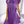 Vrouw in paarse geplooide jurk met strik, gouden kettingtas, moderne mode, elegante outfit, trendy kleding, stijlvolle dameskleding.