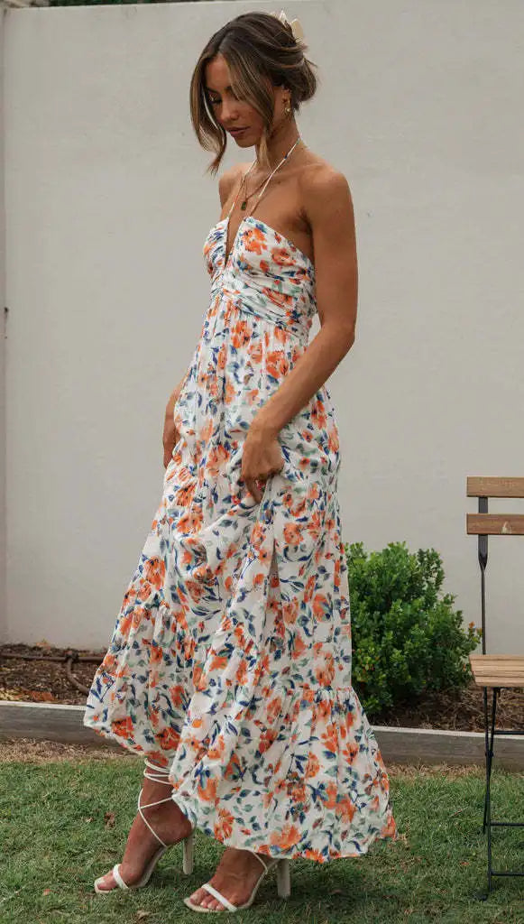 Vrouw in strapless zomerjurk met kleurrijke bloemenprint, staand in tuin. Perfect voor zomermode, casual stijl, elegante uitstraling.