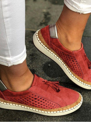 Rode suède damessneakers met geperforeerd ontwerp en kwastjes, gedragen met witte broek. Comfortabele casual schoenen voor dagelijks gebruik.