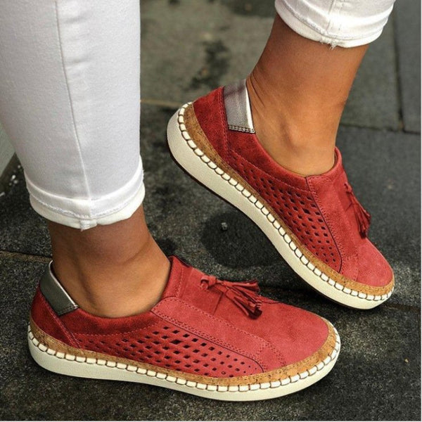 Rode suède damessneakers met geperforeerd ontwerp en kwastjes, gedragen met witte broek. Comfortabele casual schoenen voor dagelijks gebruik.