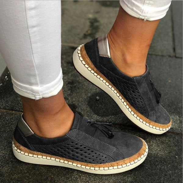 Donkergrijze suède damessneakers met geperforeerd ontwerp en witte zolen, gedragen met witte broek. Comfortabele casual schoenen voor dagelijks gebruik.
