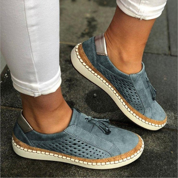 Blauwe suède damessneakers met geperforeerd ontwerp en kwastjes, comfortabele casual schoenen, gedragen met witte broek op stoep.