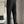 Man in zwarte broek en witte blouse in moderne woonkamer, stijlvolle mode, comfortabele kleding, minimalistisch interieurontwerp.