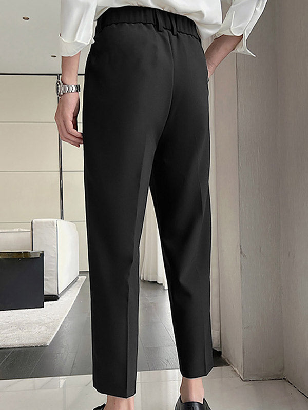 Man in zwarte broek en witte blouse in moderne woonkamer, stijlvolle mode, comfortabele kleding, minimalistisch interieurontwerp.